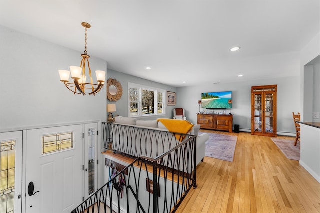 foyer with a baseboard radiator, recessed lighting, light wood-style flooring, an inviting chandelier, and baseboards