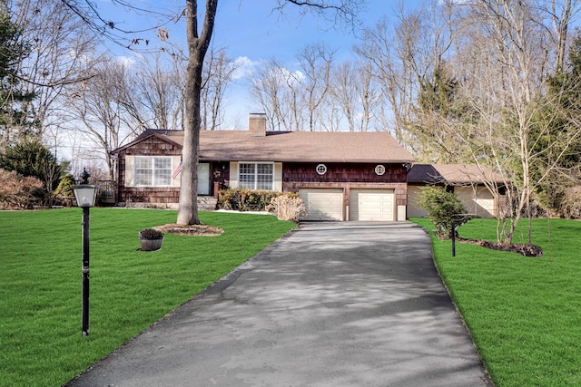 single story home featuring an attached garage, driveway, a chimney, and a front yard