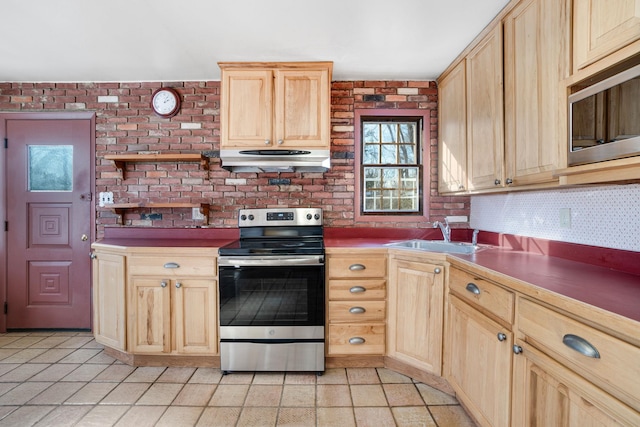 kitchen with light brown cabinetry, appliances with stainless steel finishes, a sink, brick wall, and extractor fan