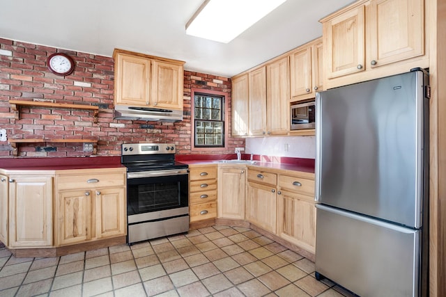 kitchen featuring brick wall, stainless steel appliances, ventilation hood, and light brown cabinets