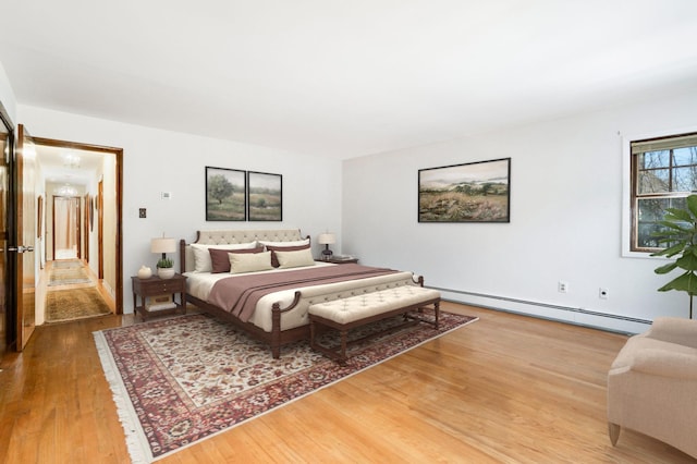 bedroom with a baseboard radiator and wood finished floors