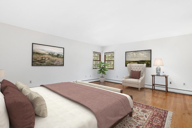 bedroom with a baseboard heating unit, baseboard heating, and hardwood / wood-style floors