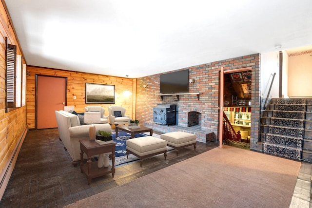 living room with wood walls, stairway, a baseboard radiator, and a wood stove