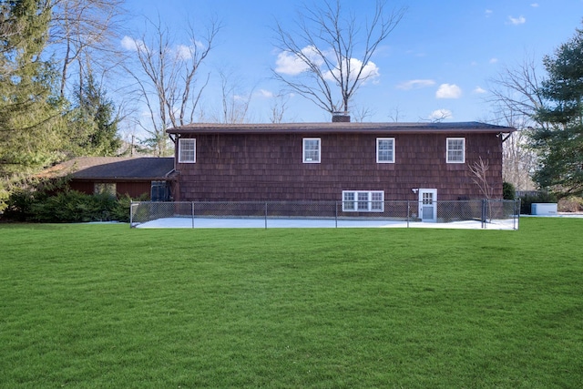 back of property featuring a lawn, a chimney, and fence