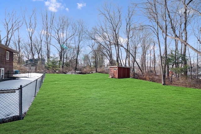 view of yard featuring fence, a storage unit, and an outbuilding