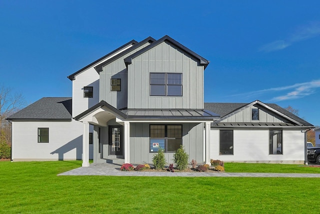 back of property with a standing seam roof, board and batten siding, and a lawn