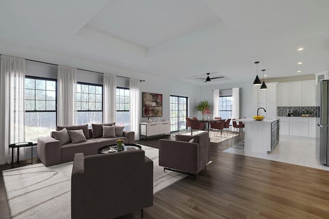 living room featuring plenty of natural light, a tray ceiling, wood finished floors, and recessed lighting