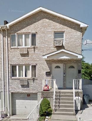 view of front of house featuring a garage, cooling unit, and brick siding