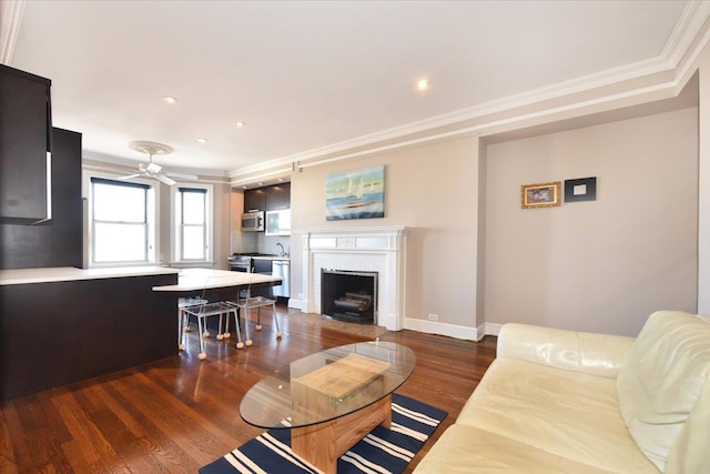 living area with ornamental molding, wood finished floors, recessed lighting, baseboards, and a brick fireplace