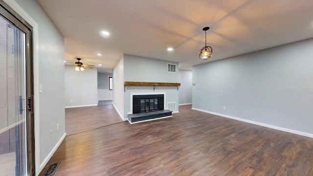 unfurnished living room featuring visible vents, baseboards, a glass covered fireplace, dark wood-style floors, and recessed lighting