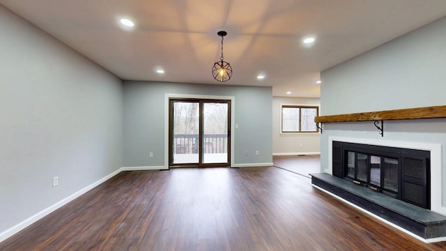 unfurnished living room with dark wood-style floors, a glass covered fireplace, baseboards, and recessed lighting