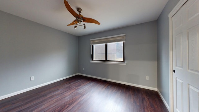 spare room with dark wood-style floors, a ceiling fan, and baseboards