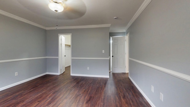 empty room featuring crown molding, dark wood-type flooring, and baseboards