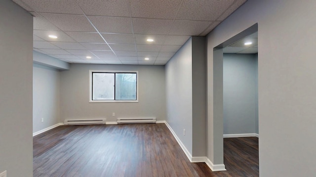 empty room with a baseboard heating unit, recessed lighting, wood finished floors, and baseboards