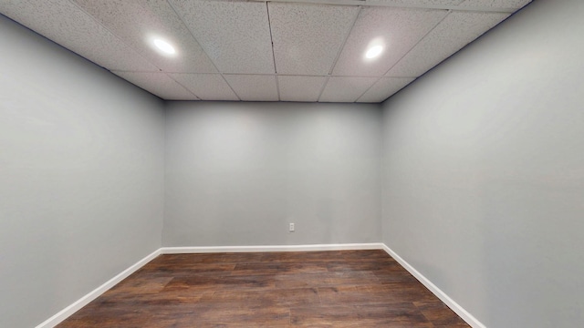 unfurnished room with a paneled ceiling, baseboards, and wood finished floors