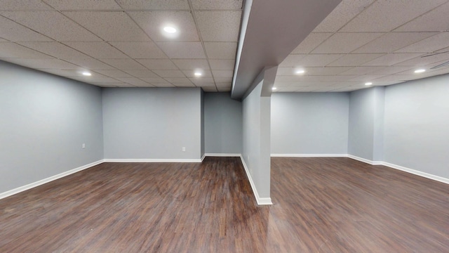 finished below grade area featuring a drop ceiling, wood finished floors, and baseboards