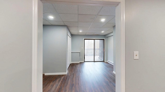 unfurnished room with dark wood-style floors, recessed lighting, baseboard heating, a drop ceiling, and baseboards