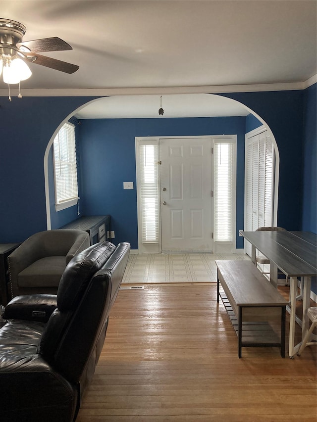 entryway with arched walkways, plenty of natural light, light wood finished floors, and ceiling fan