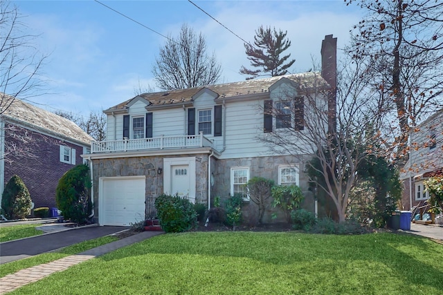 view of front facade featuring a balcony, stone siding, a chimney, aphalt driveway, and a front yard