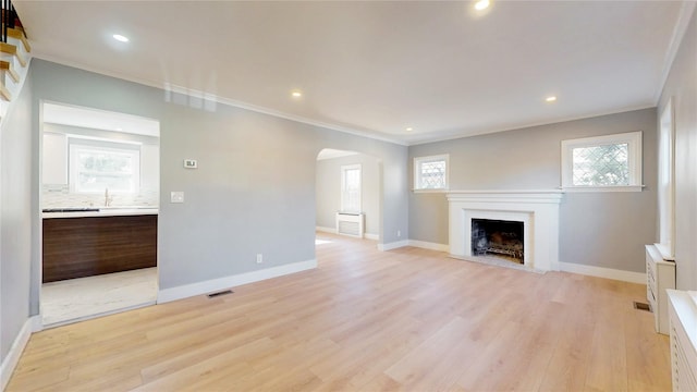 unfurnished living room with light wood-style flooring, baseboards, and a fireplace with raised hearth