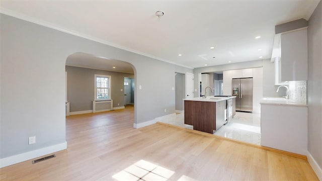 kitchen with arched walkways, visible vents, white cabinetry, modern cabinets, and stainless steel fridge with ice dispenser