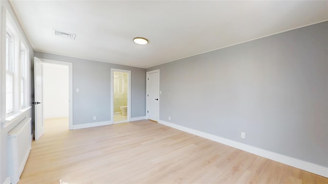 unfurnished bedroom featuring light wood-type flooring, visible vents, connected bathroom, and baseboards