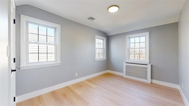 spare room featuring lofted ceiling, baseboards, visible vents, and wood finished floors