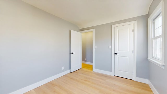 unfurnished bedroom with multiple windows, light wood-style flooring, and baseboards