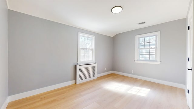 spare room with light wood-style floors, visible vents, and baseboards