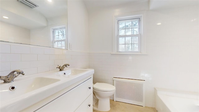 full bathroom featuring toilet, visible vents, tile walls, radiator heating unit, and a bathtub