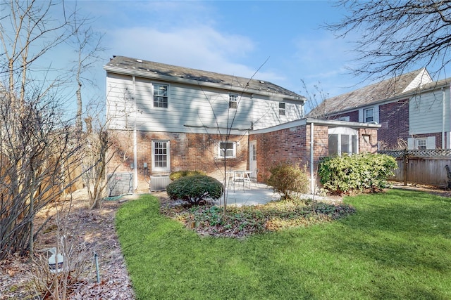 back of property featuring fence, a lawn, a patio, and brick siding