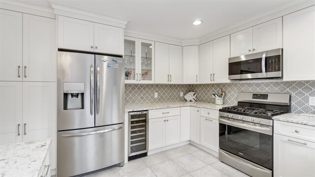 5225 Peconic Bay Blvd, Laurel, NY 11948 - kitchen with appliances with stainless steel finishes, beverage cooler, white cabinetry, and decorative backsplash