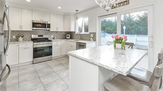 kitchen featuring stainless steel appliances, white cabinetry, decorative backsplash, and light stone countertops