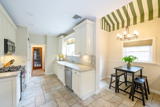 kitchen featuring stainless steel appliances, visible vents, white cabinetry, a sink, and a chandelier