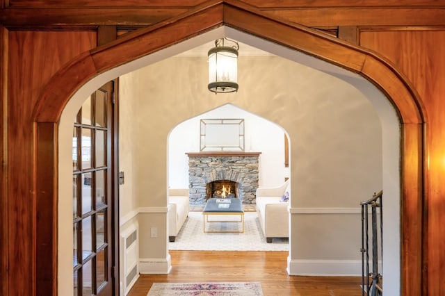 interior space with arched walkways, a fireplace, wood finished floors, and baseboards