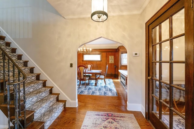 foyer entrance with stairway, arched walkways, wood finished floors, and ornamental molding