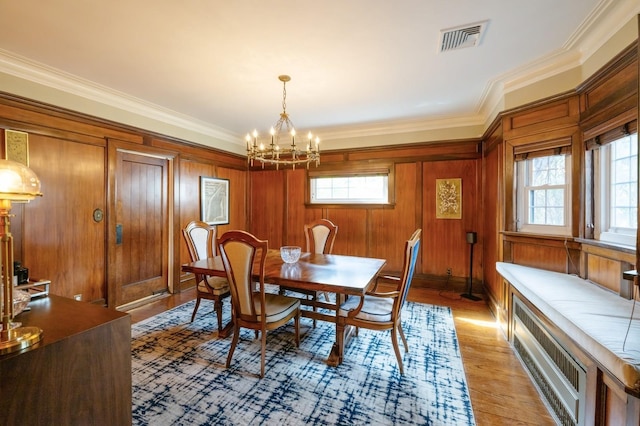 dining space featuring crown molding, light wood-style floors, visible vents, and a notable chandelier