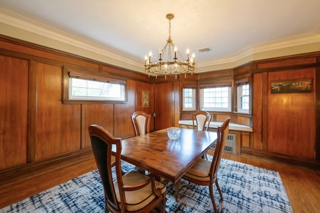 dining area featuring ornamental molding, wood finished floors, visible vents, and a notable chandelier