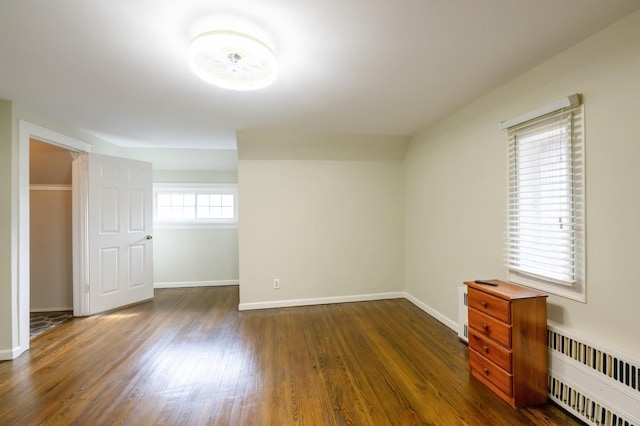 empty room with baseboards, dark wood finished floors, and radiator