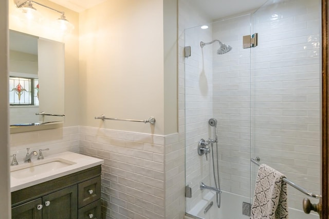 bathroom with wainscoting, tile walls, tiled shower, and vanity