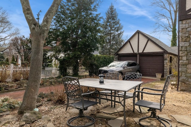 view of patio featuring a garage, an outbuilding, outdoor dining area, and fence