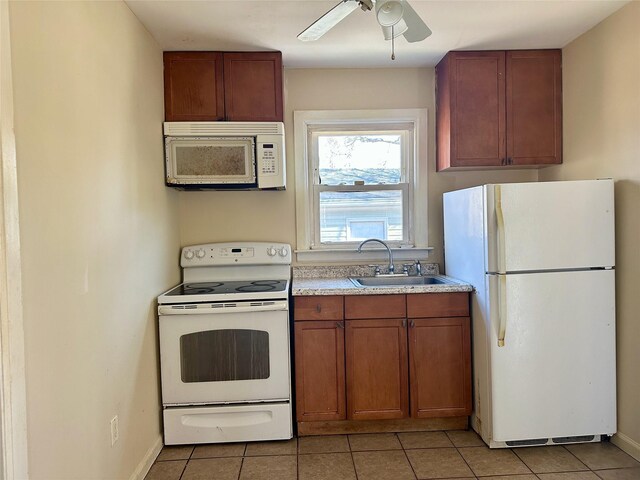 kitchen with white appliances, light tile patterned floors, light countertops, and a sink