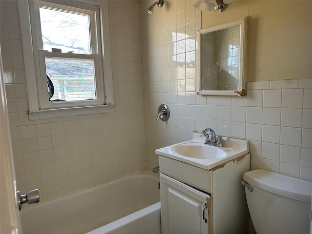 bathroom featuring toilet, washtub / shower combination, vanity, and tile walls