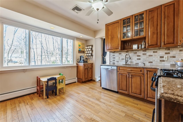 kitchen featuring stainless steel appliances, brown cabinetry, light wood-type flooring, and a sink