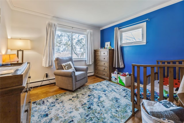 bedroom with crown molding, a baseboard heating unit, and wood finished floors