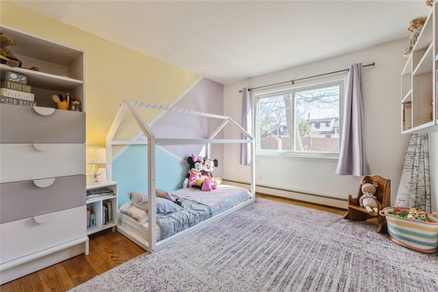 bedroom with a baseboard radiator and wood finished floors