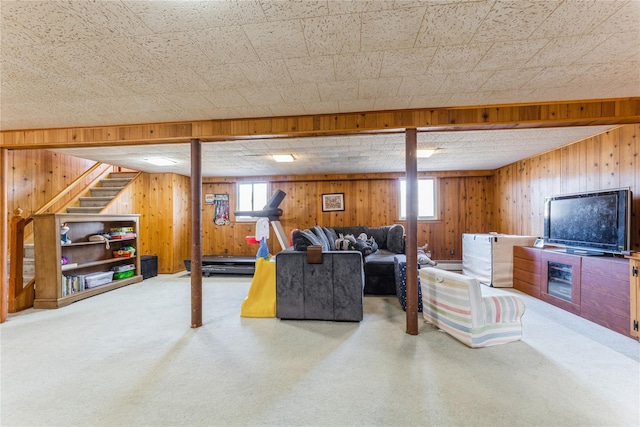 carpeted living area with wood walls, stairs, baseboard heating, and a wealth of natural light