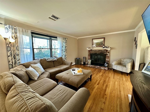 living room featuring ornamental molding, hardwood / wood-style floors, a fireplace, and visible vents