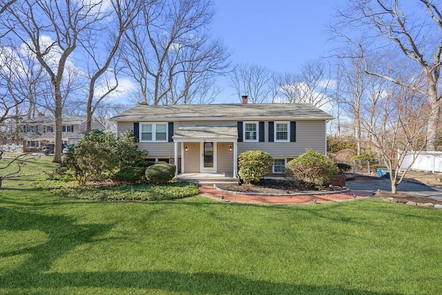 raised ranch with a chimney and a front lawn