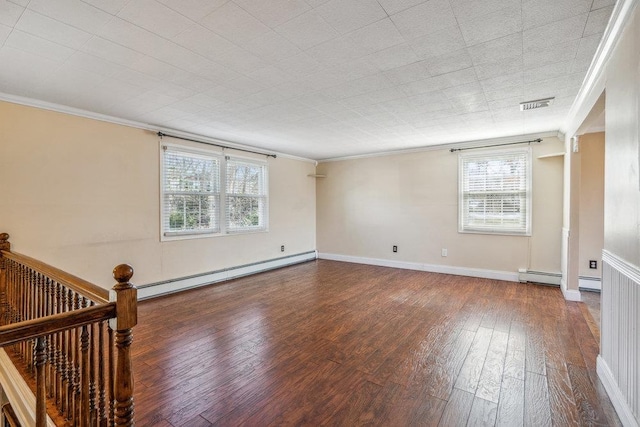 empty room featuring baseboards, visible vents, ornamental molding, hardwood / wood-style floors, and baseboard heating